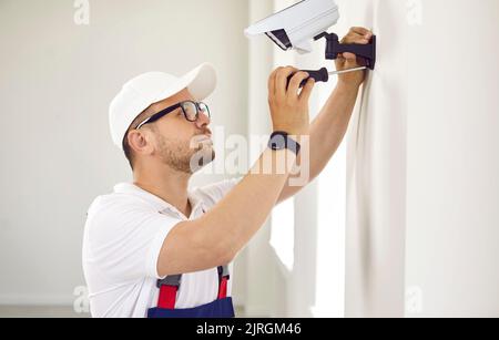 Worker installing a surveillance CCTV camera on the wall inside the house or office Stock Photo