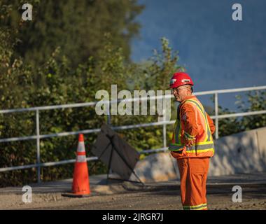 Road worker construction. Road workers inspecting construction. Engineer worker tablet working on site road construction. Cone worker asphalting-Augus Stock Photo