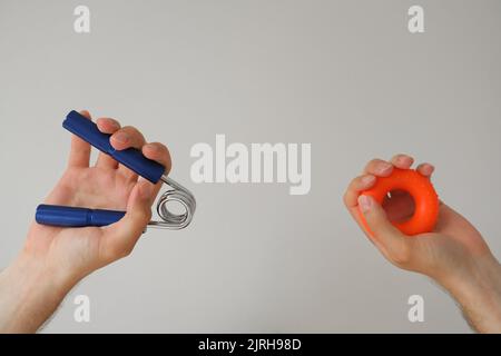 man hands holding gym wrist strength exerciser, wrist rehabilitation developer, fitness and sports equipment concept on minimal white background with Stock Photo