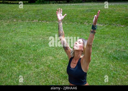Young european lady with outstretched arms, wearing tattoos and piercings Stock Photo
