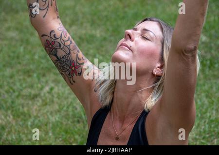 Young european lady with outstretched arms, wearing tattoos and piercings Stock Photo