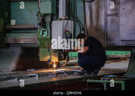 Worker operates drilling machine in factory workshop Stock Photo