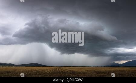 Destructive supercell storm bringing rain and wind over the farm field Stock Photo