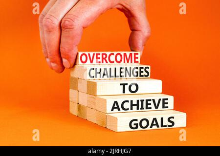 Overcome challenges to achieve goals symbol. Concept words Overcome challenges to achieve goals on wooden blocks on a beautiful orange background. Bus Stock Photo