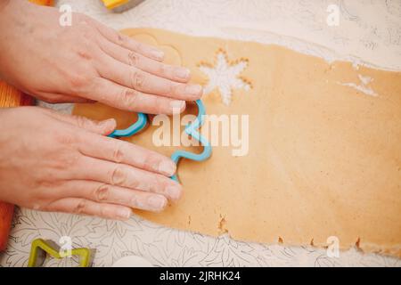 Woman hands form molds cutters ginger dough and makes delicious christmas ginger cookies. Cooking and decorating christmas dessert flour Stock Photo
