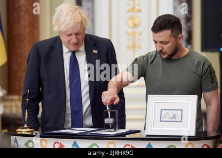 Kyiv, Ukraine. 24th Aug, 2022. British Prime Minister Boris Johnson, left, looks on as Ukrainian President Volodymyr Zelenskyy, cancels the first set of the newly issued postage stamp marking the last six month of the Russian Invasion during a ceremony at the Mariinsky Palace, August 24, 2022 in Kyiv Ukraine. The stamp called “Free, Unbreakable, Unbeatable”, was released for the 31st anniversary of Ukraine independence. Credit: Sarsenov Daniiar/Ukraine Presidency/Alamy Live News Stock Photo