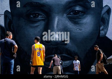 Los Angeles, California, USA. 24th Aug, 2022. People take photos a mural depicting Kobe Bryant and his daughter, Gianna in Los Angeles, Wednesday, August 24, 2022. To mark Mamba Day 2022, a 125 feet by 32 feet giant outdoor mural depicting a close-up of Kobe Bryant's face, in black-and-white, in the middle, flanked by a mamba snake on the left and, in color, a group of children including Bryant's daughter Gianna playing basketball atop a giant book, is unveiled on an entire side of a building near former Staples Center. (Credit Image: © Ringo Chiu/ZUMA Press Wire) Stock Photo