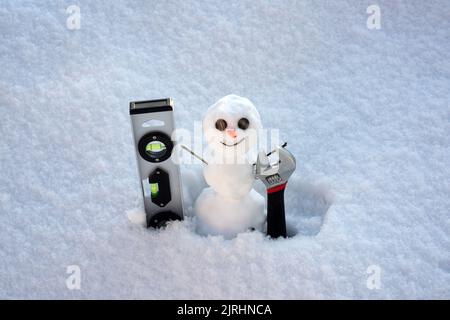 Snow man. Repairman with repair tools. Support repair and recover service. Snowman isolated on snow background. Stock Photo