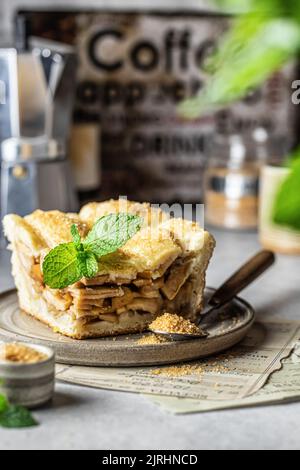 Piece of traditional apple pie with mint leave on ceramic plate, cozy rustic still life, fall baking concept Stock Photo