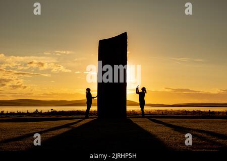 Orkney, UK. 24th Aug, 2022. Two women are dwarfed as they stand next to a stone in the Standing Stones of Stenness, Orkney, as the sun sets. The 5,000 year old massive stones are part of the Heart of Neolithic Orkney World Heritage Site. Credit: Peter Lopeman/Alamy Live News Stock Photo