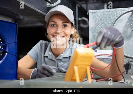 female electrician testing charge to spotlight Stock Photo
