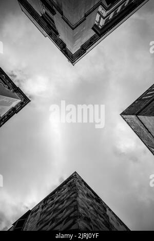 A vertical shot of a gloomy sky and corners of buildings inn grayscale Stock Photo