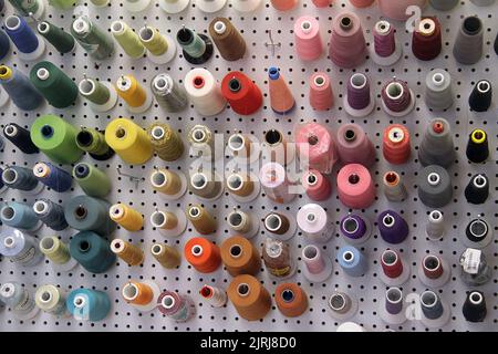 Various colorful sewing spools nicely organized on a pegboard Stock Photo