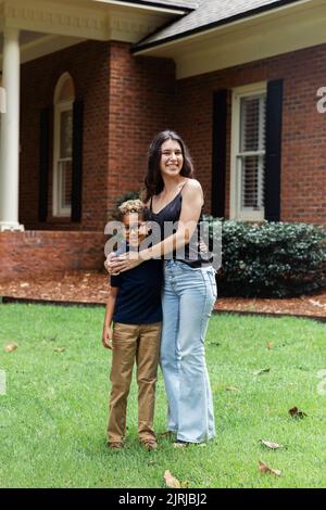 A big sister hugging on her little brother outside their home Stock Photo