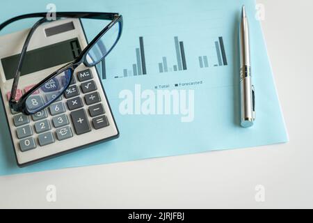 Eyeglasses, calculator and pen on top of report with charts. Financial analysis and market trends concept. Stock Photo
