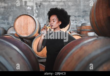 Black winemaker smelling white wine in vineyard cellar, expert analysis by professional, proud female sommelier. Small business owner checking the Stock Photo