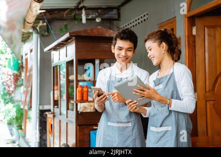 female and male sellers using tablet and mobile phone Stock Photo