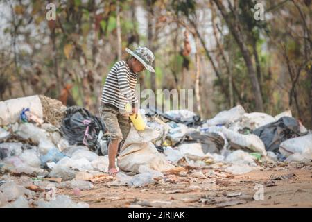 A poor boy collects trash from a landfill in the suburbs. Life and way of life of the poor Concept of child labor, poverty, environment. Waste separat Stock Photo