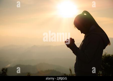 woman praying in the morning concept of christianity rising sun background Concept of prayer, faith, hope, love, liberation. Stock Photo