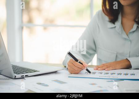 Business man work on statistics and business graphs, Businessman holding a pen is working with graph documents, Stock market chart. Stock Photo