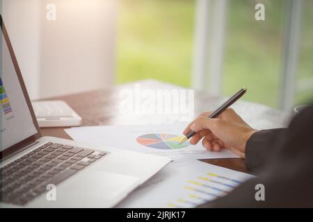 Hand of businessman writing on paper in office, graphs showing the results of their successful teamwork, Stock Photo
