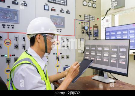 Male engineerr working in electrical control room in the heavy factory. Professional industrial engineer operating in electricity substation. Stock Photo