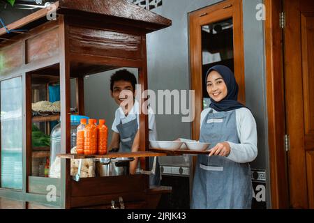 smiling two sellers preparing chicken noodles dish with bowls Stock Photo