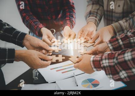 Hands of diverse people assembling jigsaw puzzle, team put pieces together searching for right match, help support in teamwork to find common solution Stock Photo