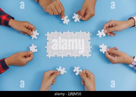 Group of business people assemble jigsaw puzzles on blue background,  teamwork, help and support in business, symbol of association and connection. bu Stock Photo