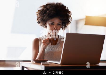 Start small and build on your success. a young business owner using a laptop while sitting in her cafe. Stock Photo
