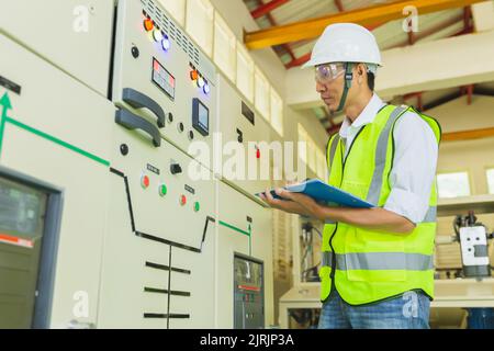 Experienced electrician working in power plant control room. Engineer working on the checking status switchgear electrical energy distribution substat Stock Photo