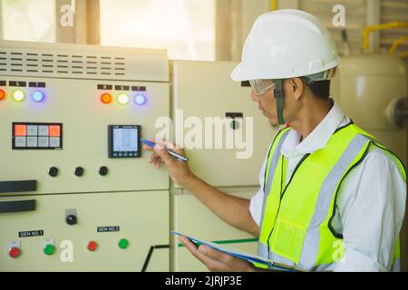 Electrical engineers test the voltage and current of the wires in the electrical cabinet control.the multimeter is in the hands of the electrician det Stock Photo