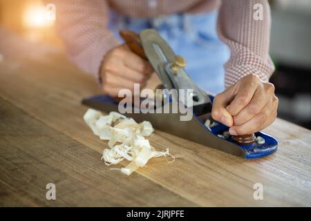 A carpenter works with equipment on a wooden table in a carpentry shop. Stock Photo