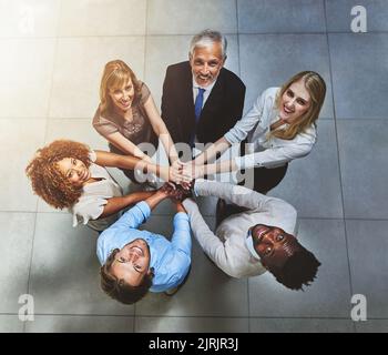 Collaboration makes us a better team. High angle shot of a group of colleagues joining their hands in solidarity. Stock Photo