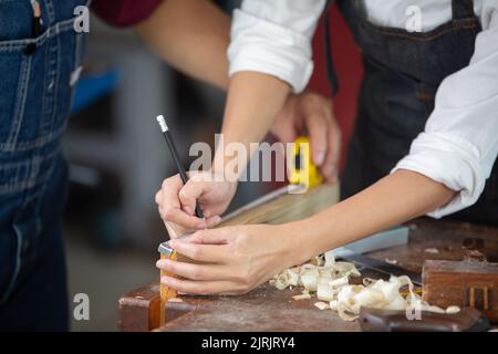 A carpenter works with equipment on a wooden table in a carpentry shop. Stock Photo