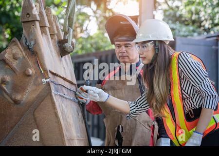 Asian female engineer checks workers' welds Stock Photo
