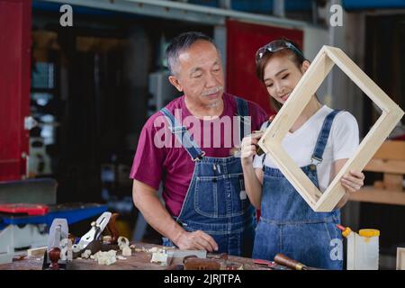 Two professional carpenters works in her own woodworking shop. Carpenter work on wood plank in workshop. small business concept. Stock Photo