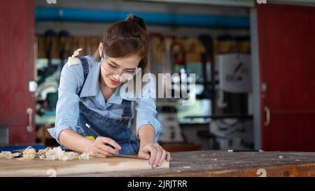 woman works in a carpentry shop. Carpenter working on woodworking machines in carpentry shop. Stock Photo