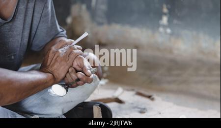 Drug addicts in the dark room. Addict/junkie preparing drugs with a spoon and lighter. White powder and a syringe. Drug concept. International drug ab Stock Photo