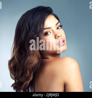 Dark haired, dark eyed beauty. Studio portrait of a beautiful young woman posing against a gray background. Stock Photo