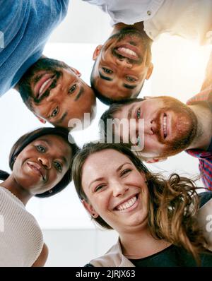 Many heads make light work. Low angle portrait of a young design team standing in a huddle in their office. Stock Photo