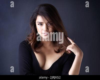 I hope your day is as nice as my hair. Studio shot of a beautiful young woman playing with her hair against a grey background. Stock Photo