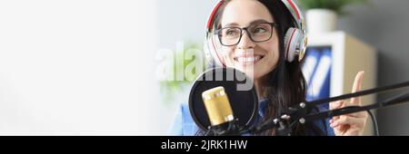 Smiling woman in headphones in front of microphone Stock Photo