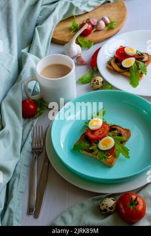 quail egg toast, Ketogenic breakfast. superfood concept. turquoise white plate latte coffee milk bread tomato arugula garlic mushrooms knife fork boil Stock Photo