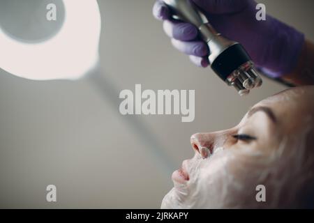 Young woman receiving electric RF lifting facial massage at beauty spa with electroporation equipment Stock Photo