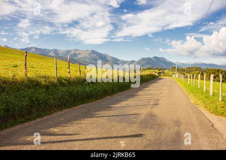Amazing landscape with mountains on background. Wide empty road in countryside. Camino de Santiago landscape. Fields with mountains on sunny day. Stock Photo