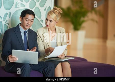 Colleagues discussing data on digital tablet and document Stock Photo