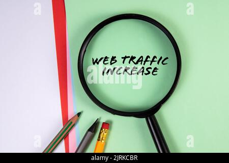 WEB TRAFFIC INCREASE. Magnifying glass on green paper background. Stock Photo