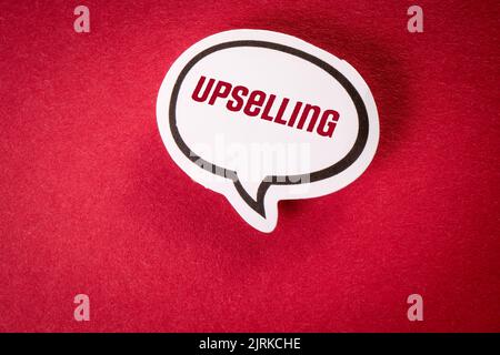 Upselling. White speech bubble with text on red background. Stock Photo