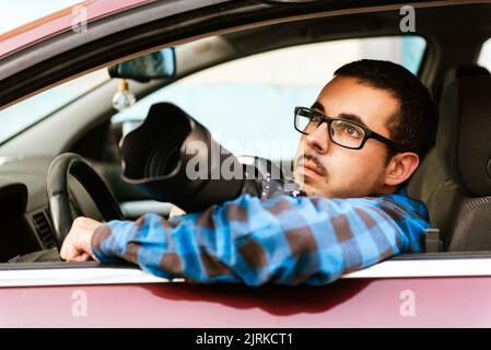 Handsome bearded male photographer in stylish outfit sitting in modern automobile while looking away Stock Photo